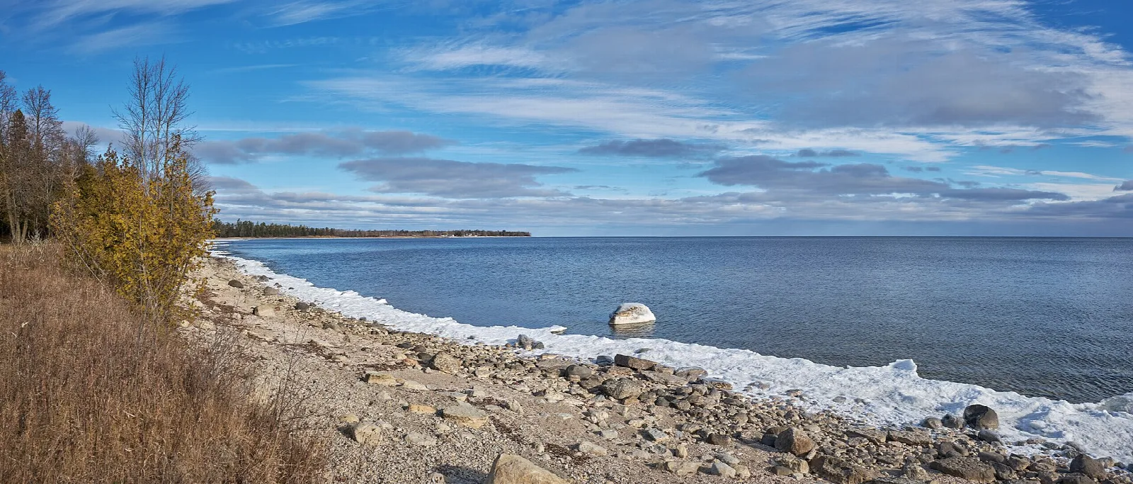 Rocky Lake Michigan shoreline with small waves under a blue sky