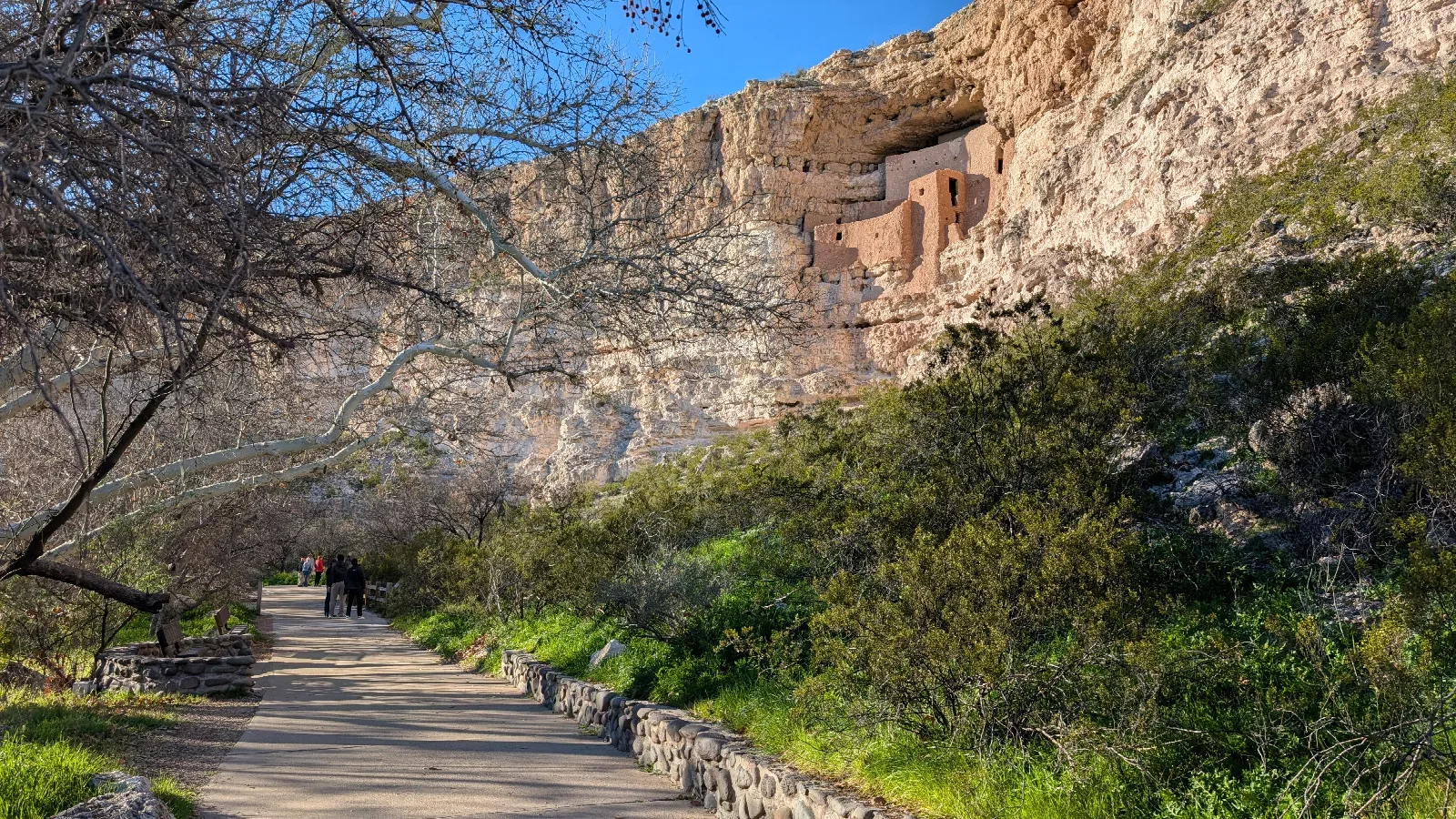 a large, multi-story adobe dwelling inside a large alcove on the side of a cliff
