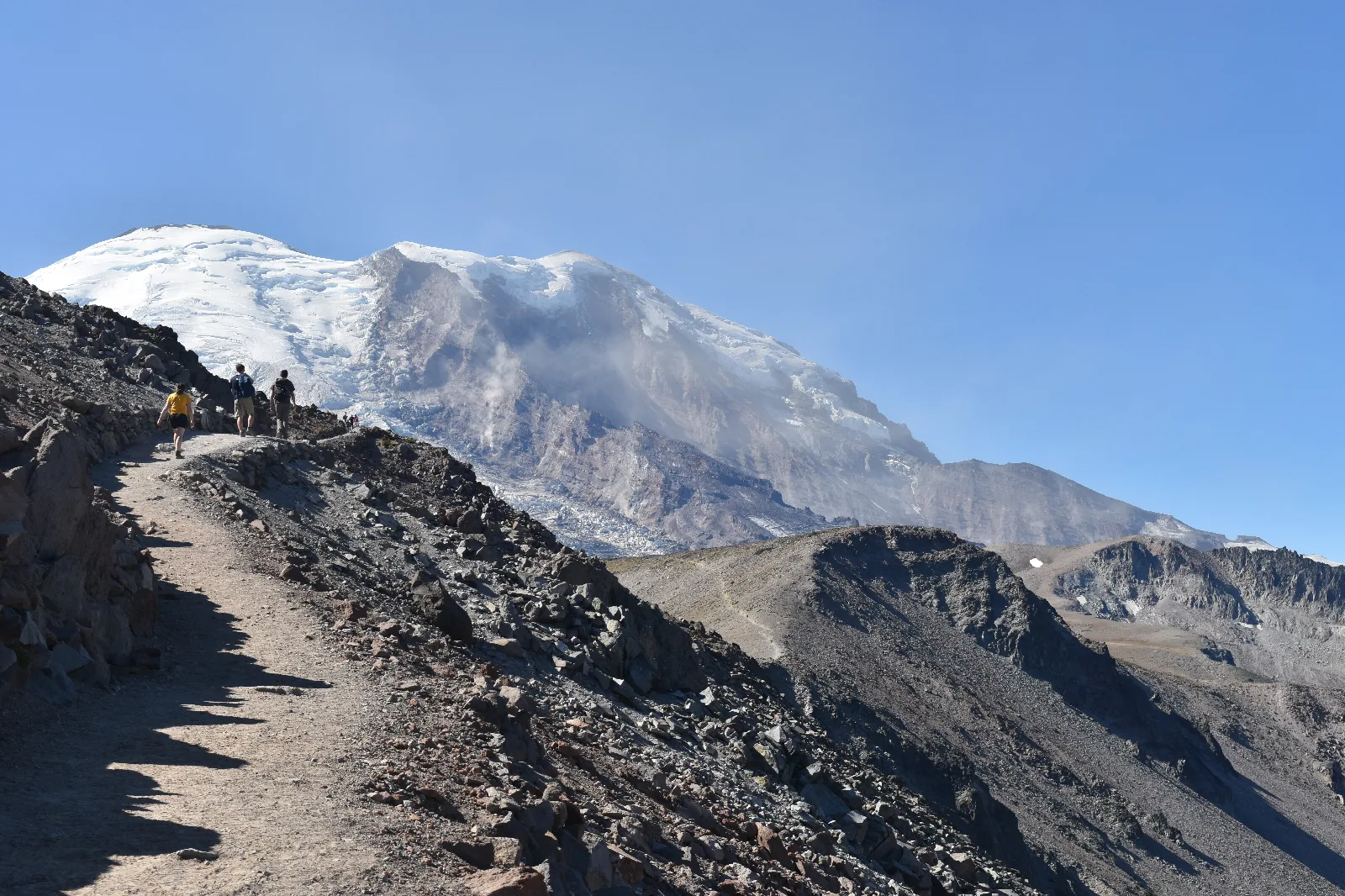 View of glaciated mountain from rolling ridgeline with three rocky peaks.